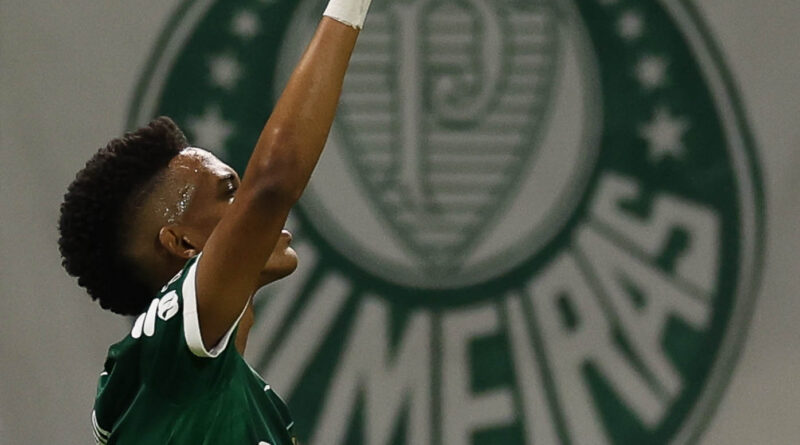 Atacante Estêvão comemora gol apontando para o céu com o escudo do Palmeiras ao fundo